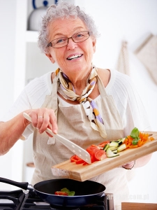 Friendly older woman happily cooking a meal